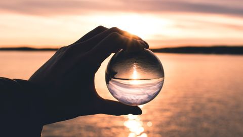 Hand mit Kristallkugel vor sepiafarbenem Horizont - Foto: canva.com