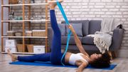 Person bei Übung mit Yoga-Gurt mit gestrecktem Bein - Foto: canva.com