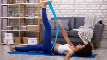 Person bei Übung mit Yoga-Gurt mit gestrecktem Bein - Foto: canva.com Person bei Übung mit Yoga-Gurt mit gestrecktem Bein - Foto: canva.com