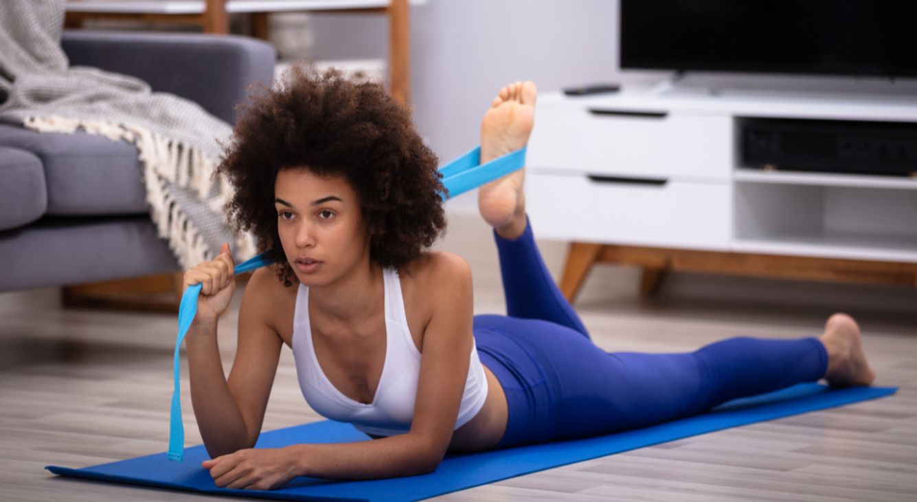 Person macht Übung mit Yoga-Gurt mit Bein 