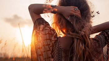 Frau von hinten im Feld bei Sonnenuntergang - Foto: Adobe Stock