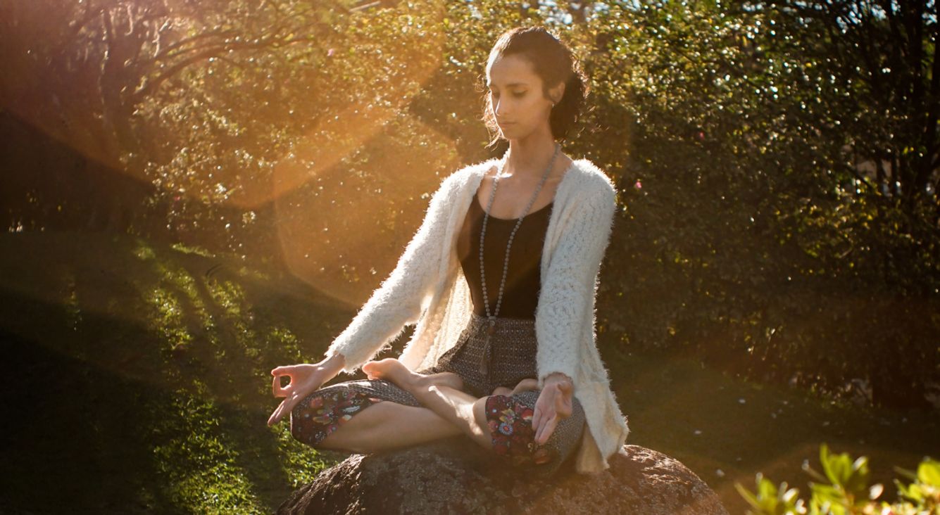 Frau meditiert auf Stein