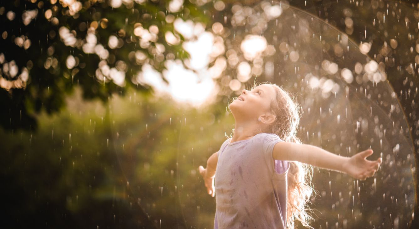 Kind tanzt um Sommerregen