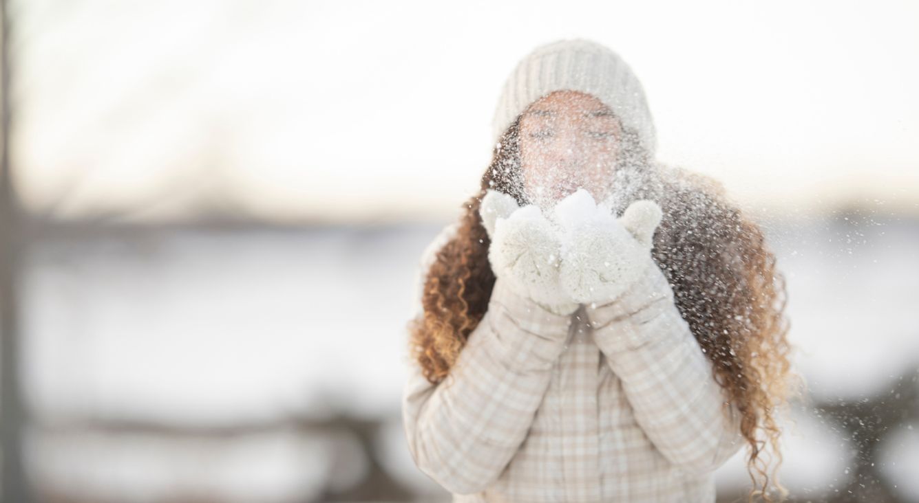 Person bläst Schnee aus Händen