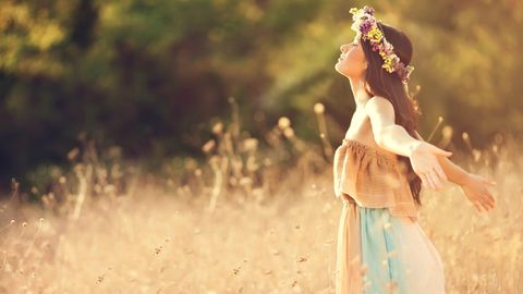 Person mit Blumenkranz in Feld - Foto: canva.com