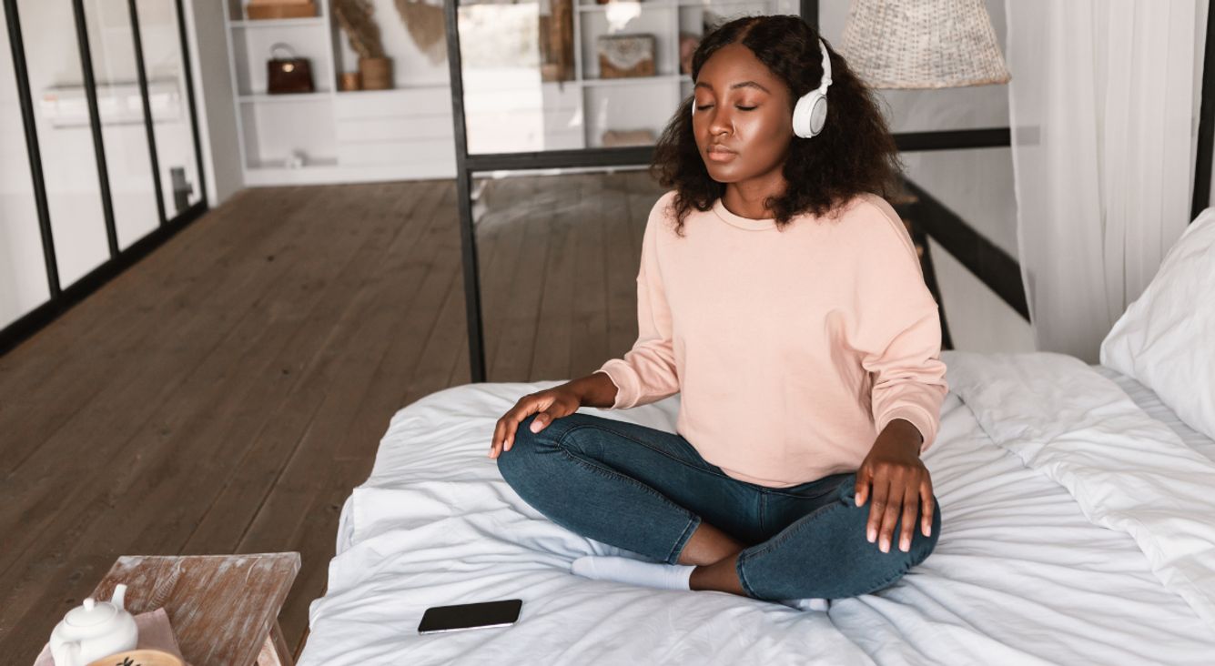 Frau auf Bett Meditation mit Handy