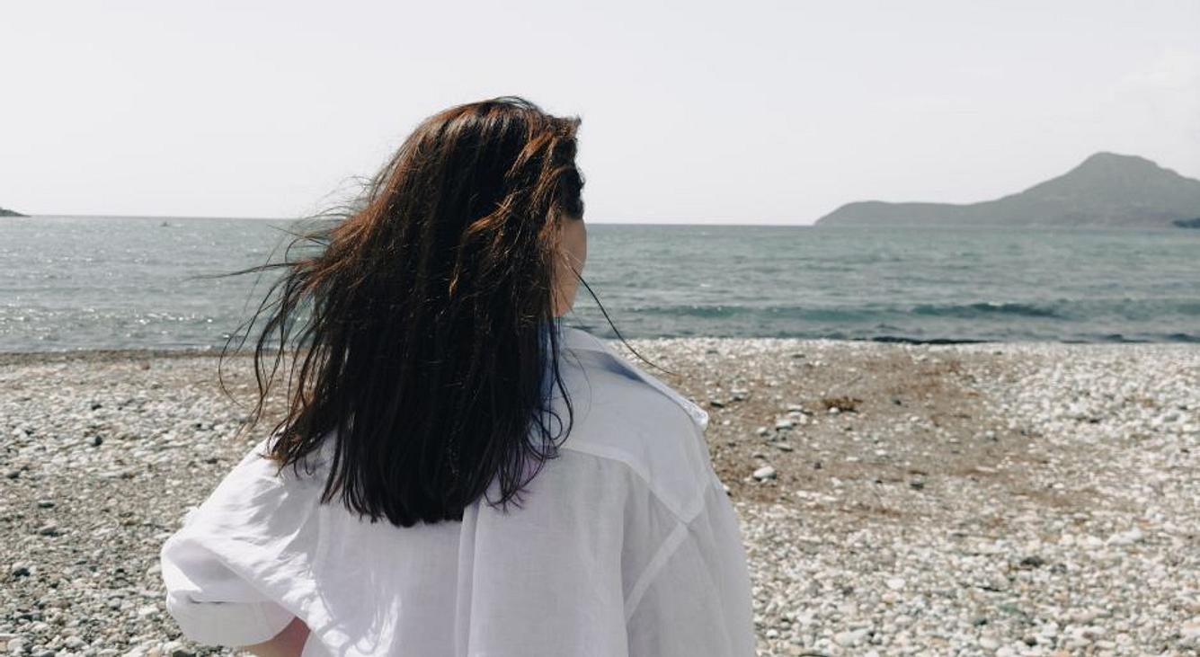 Frau am Strand, ein Berg im Hintergrund