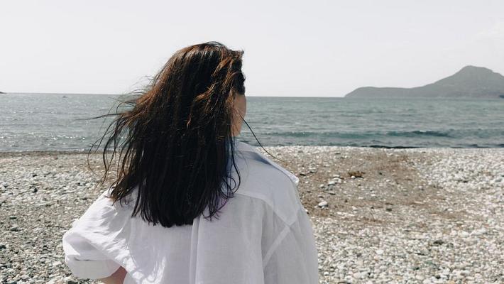 Frau am Strand, ein Berg im Hintergrund - Foto: Veronique