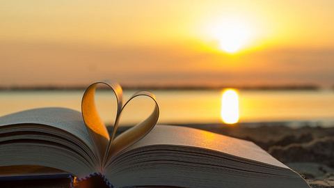 Sonnenuntergang und Buch mit Seiten die zu Herz geformt sind - Foto: canva.com