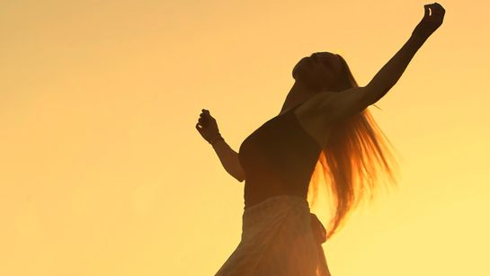 Frau jubelt mit gehobenen Armen in der Sonne  - Foto: canva