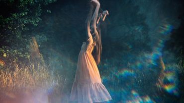 Eine Frau tanzt in der Dämmerung über eine Wiese - Foto: canva.com