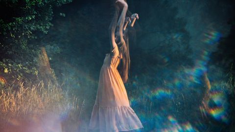 Eine Frau tanzt in der Dämmerung über eine Wiese - Foto: canva.com