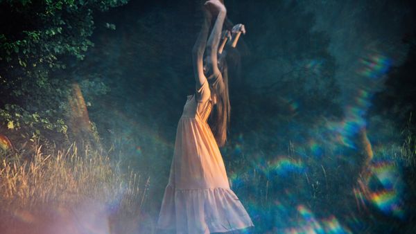 Eine Frau tanzt in der Dämmerung über eine Wiese - Foto: canva.com