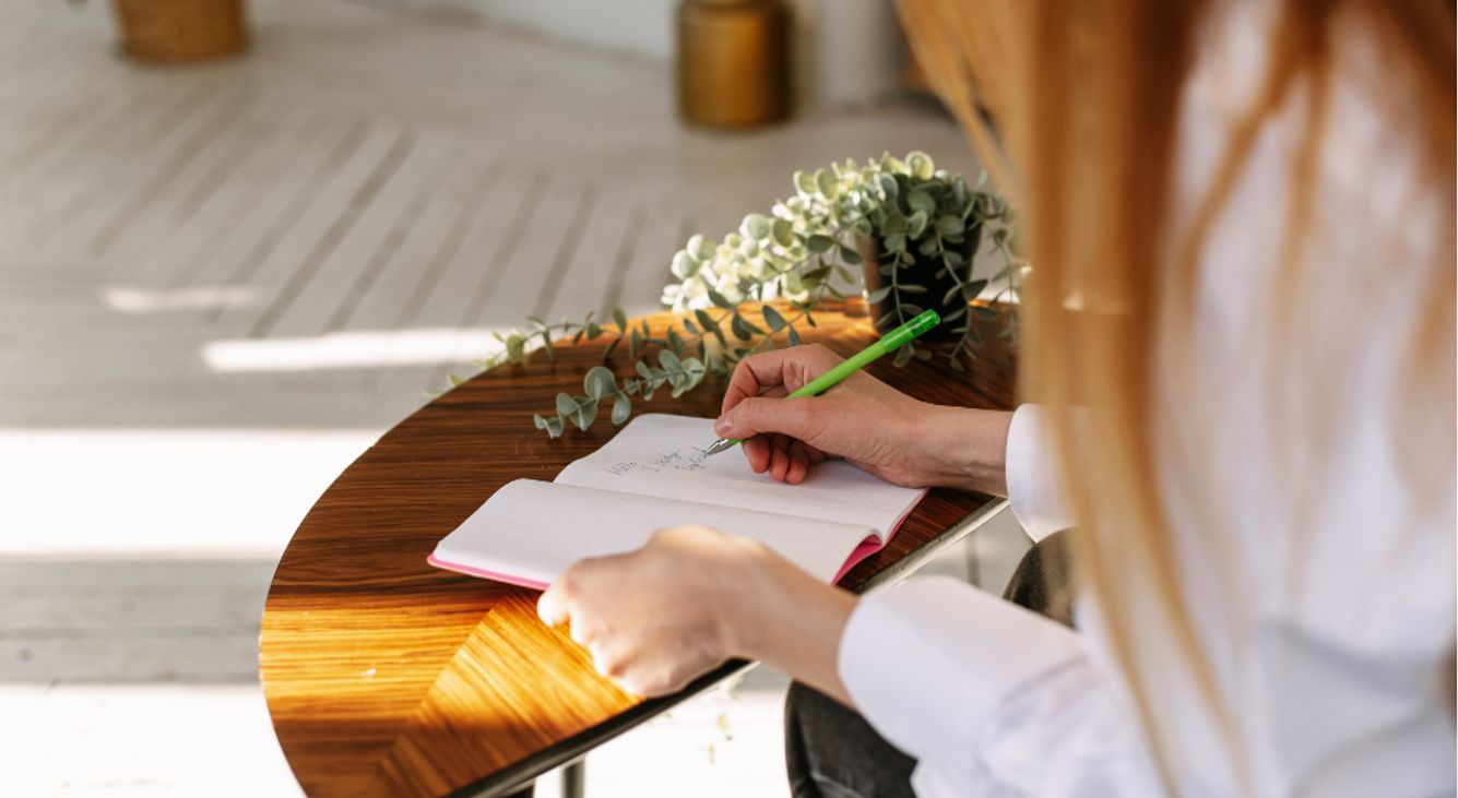 Frau beim Journaling mit Blumen auf dem Tisch