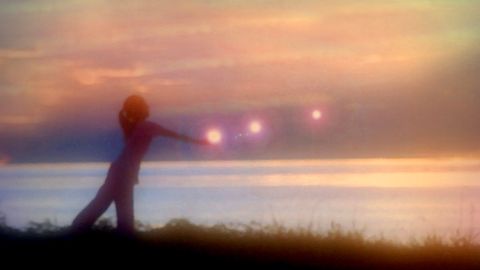Schatten einer Frau am Wasser mit ausgestreckten Armen im Sonnenuntergang - Foto: canva.com