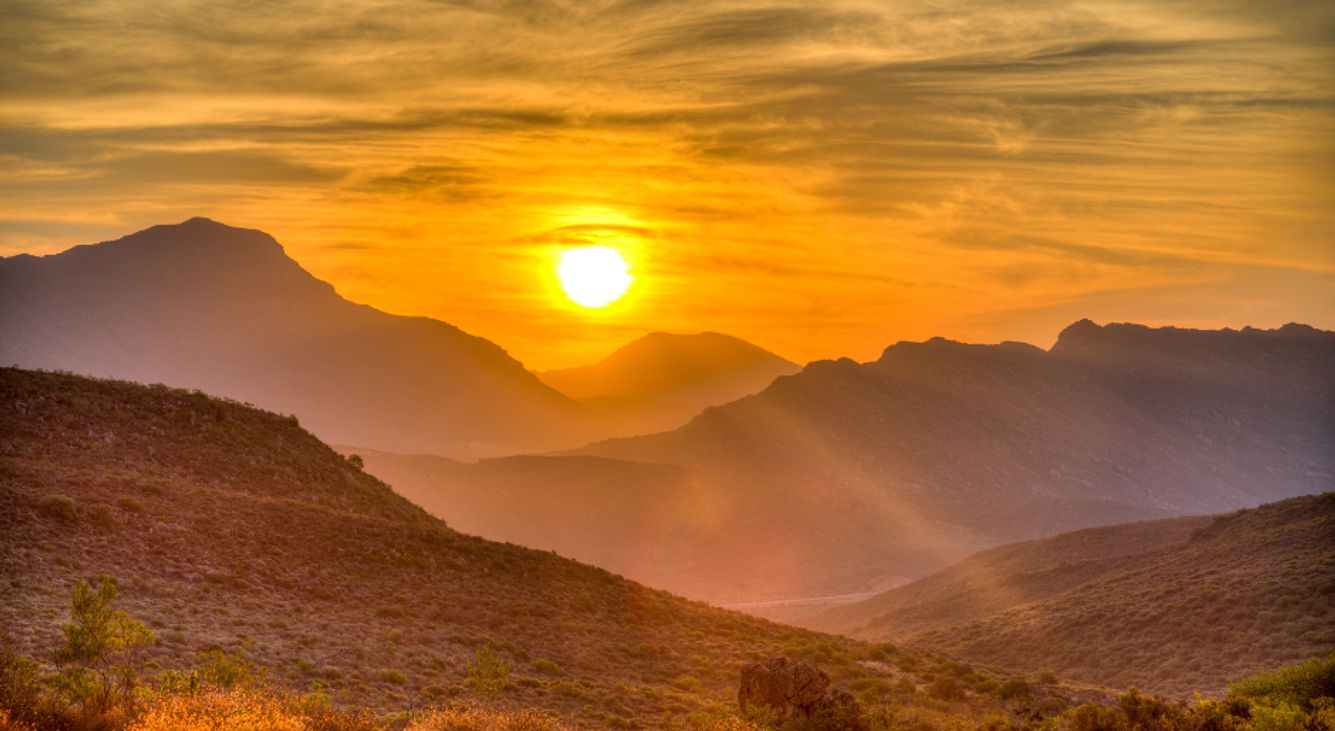 Sonne geht über einem Berg auf und taucht ihn in gelbes Licht