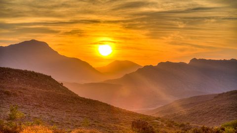 Sonne geht über einem Berg auf und taucht ihn in gelbes Licht - Foto: canva.com