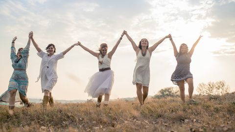 Fünf Frauen halten sich an den Händen und laufen über eine Wiese - Foto: canva.com