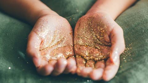 Offene Hände auf grün mit Goldstaub darin - Foto: canva.com