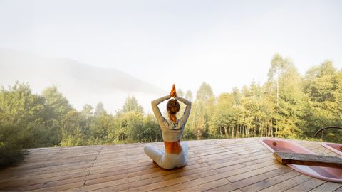 Frau macht Yoga auf Steg bei Sonnenaufgang - Foto: canva