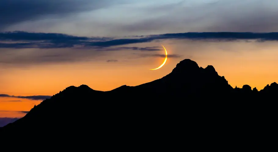 Neumond über einer Bergspitze