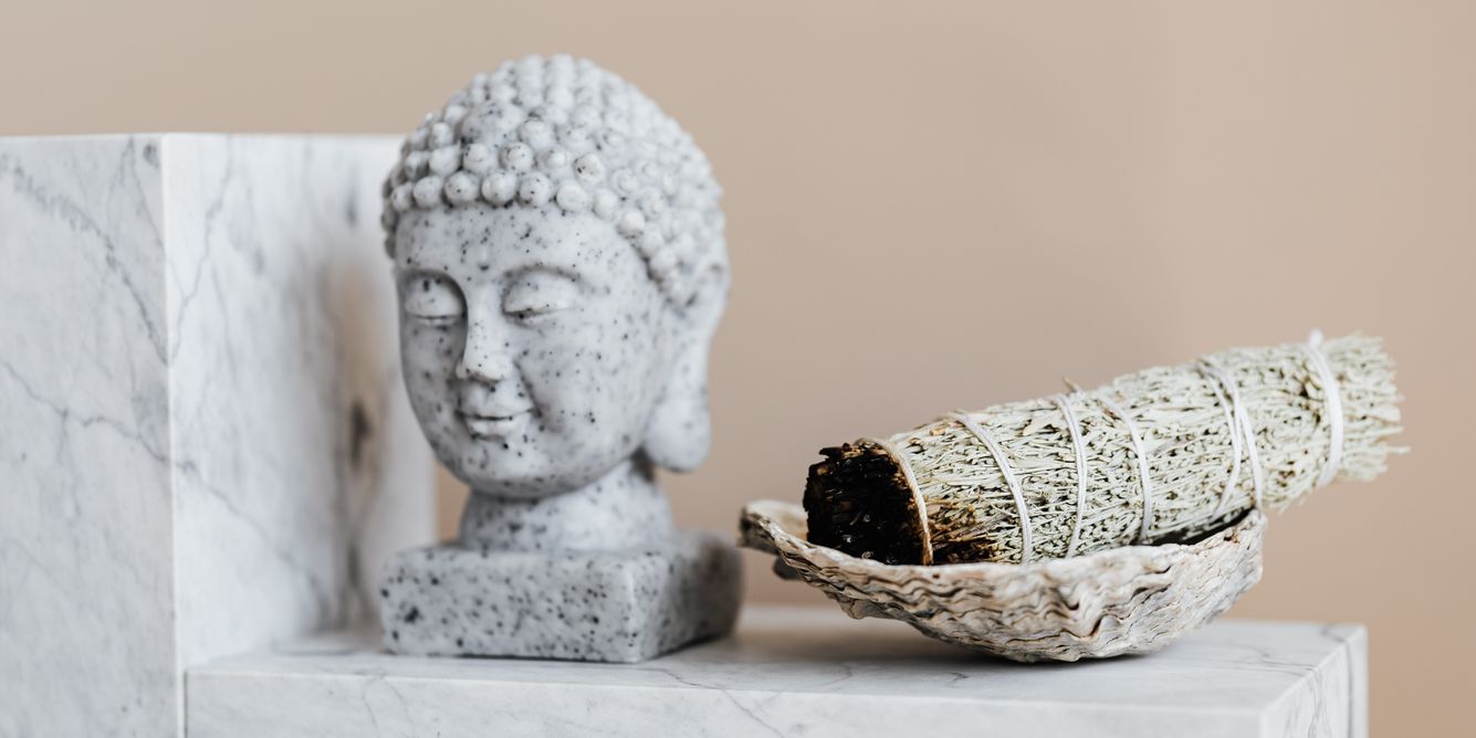 Eine Statue eines Buddha-Kopfs neben einem Räucherbündel