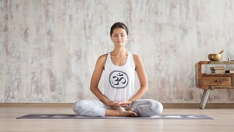 Frau im Schneidersitz auf Yoga-Matte