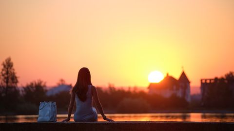 Einsame Frau sitzt an einem See und schaut den Sonnenuntergang - Foto: ANDRII BILETSKYI 