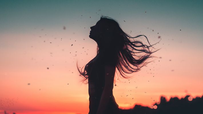 Silhouette einer Freu im Wind bei Sonnenuntergang - Foto: canva.com