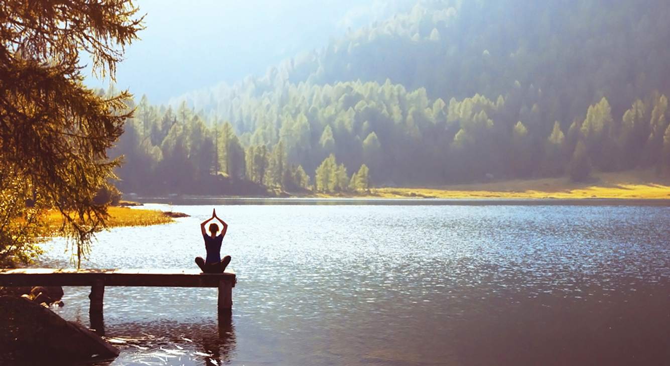 Frau macht Yoga auf Steg am See