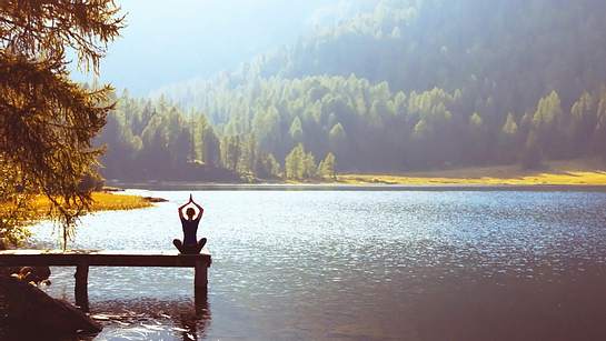 Frau macht Yoga auf Steg am See