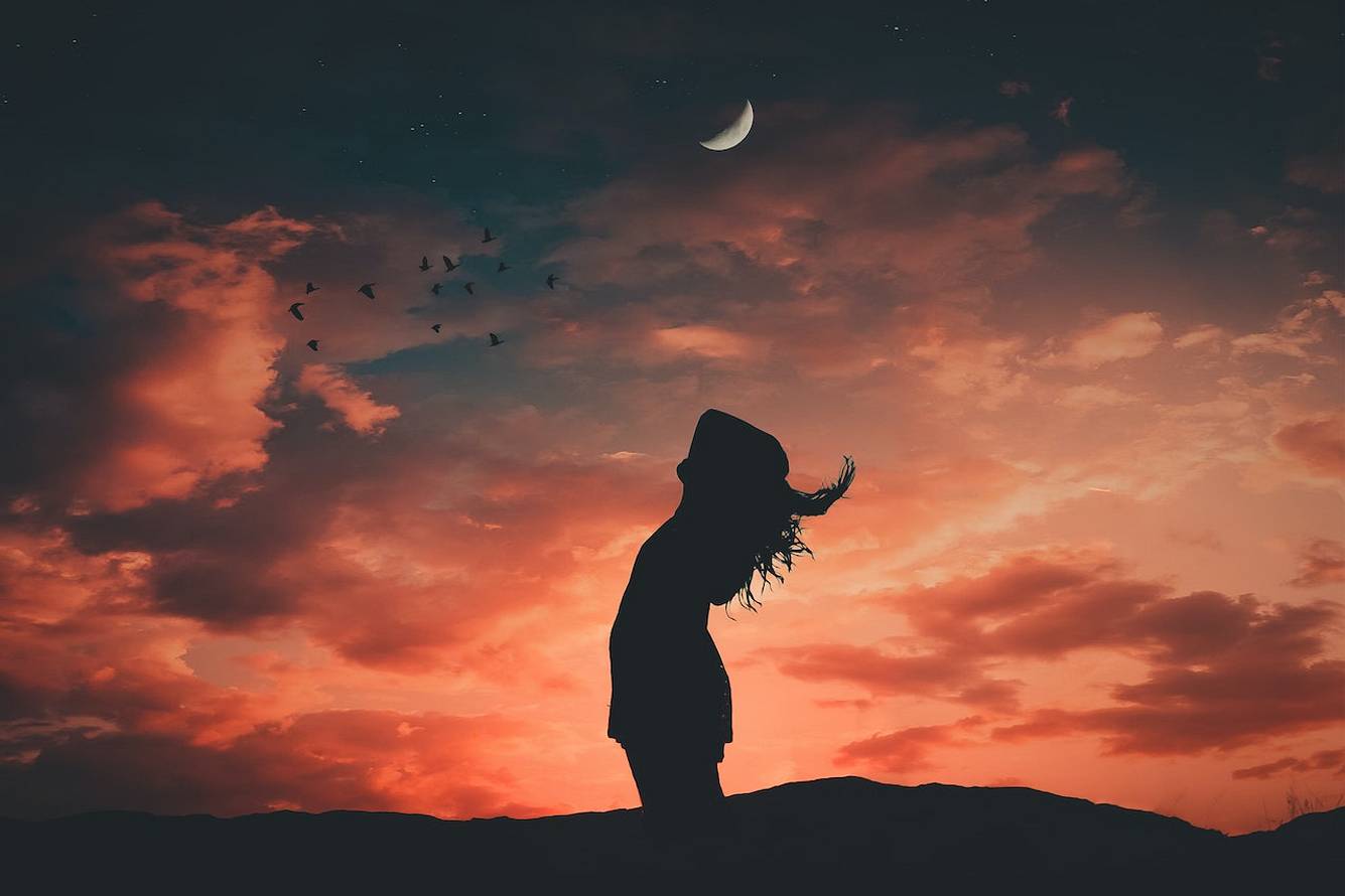 Frau steht vor rotem Himmel und Mondsichel