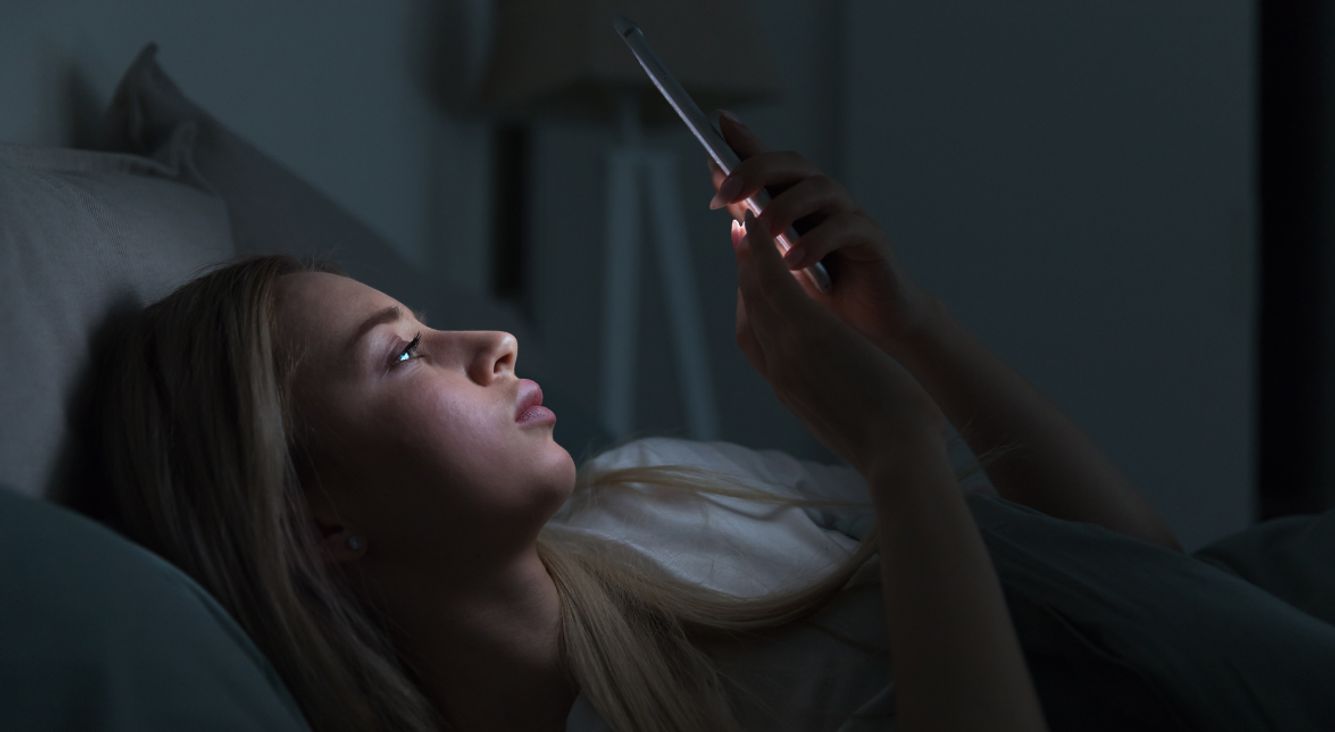 Frau mit Handy in Bett