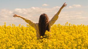 Person steht in blühendem Feld - Foto: canva.com