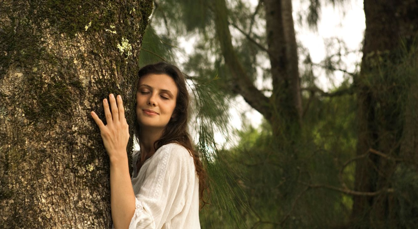 Eine Frau umarmt einen Baum im Wald