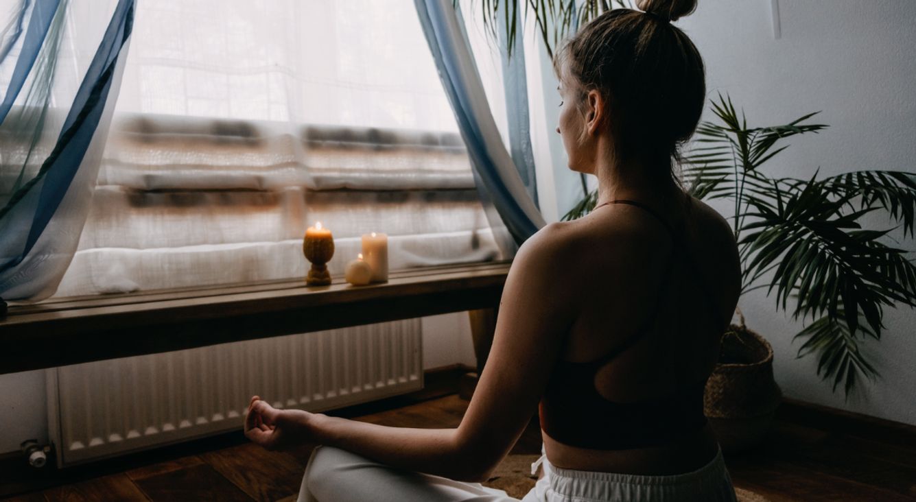 Person meditiert vor Fenster