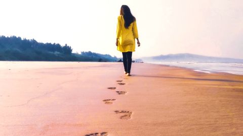 Frau hinterlässt Spuren im Sand - Foto: canva.com