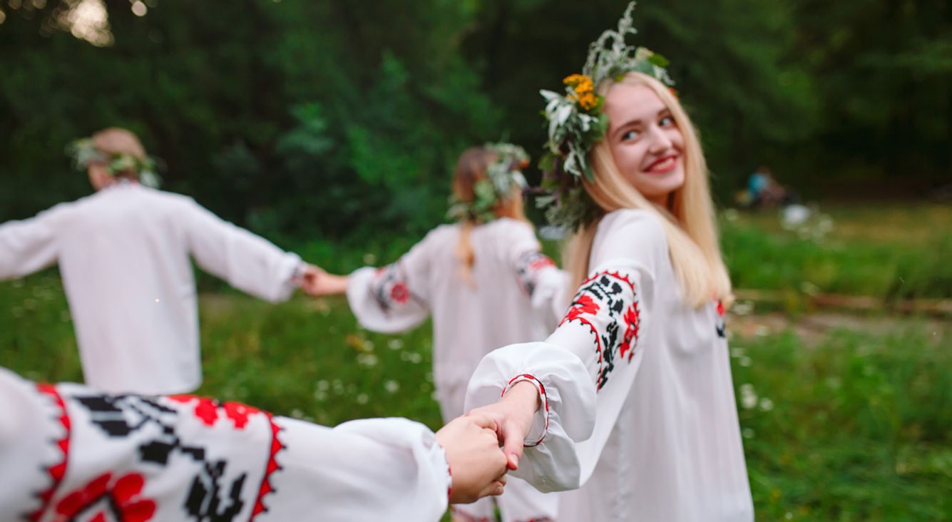 Frauen mit Blumenkränzen tanzen im Kreis