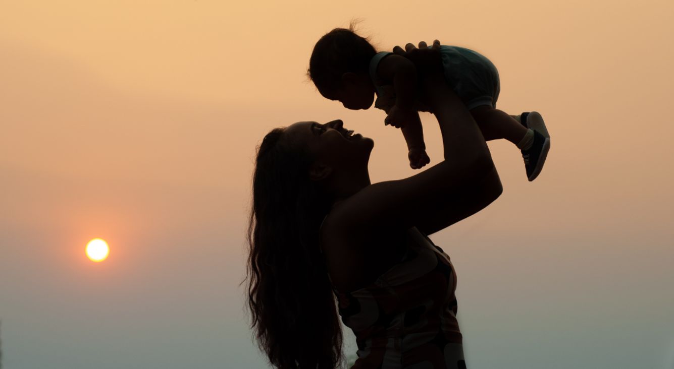 So lebst du mit deinem Kind im Rhythmus des Mondes Person hebt Baby hoch vor Himmel