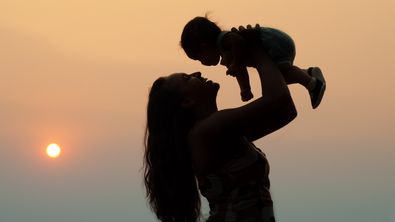 Person hebt Baby hoch vor Himmel - Foto: canva.com