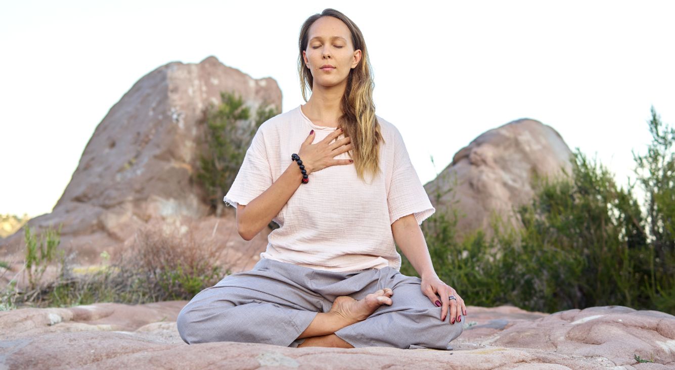 Frau bei Meditation auf Felsen