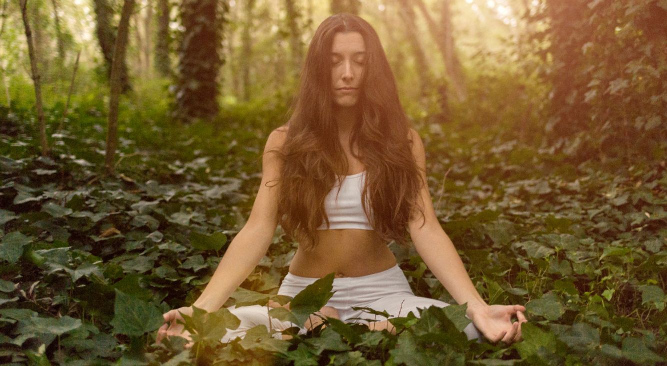 Frau meditiert auf Waldboden