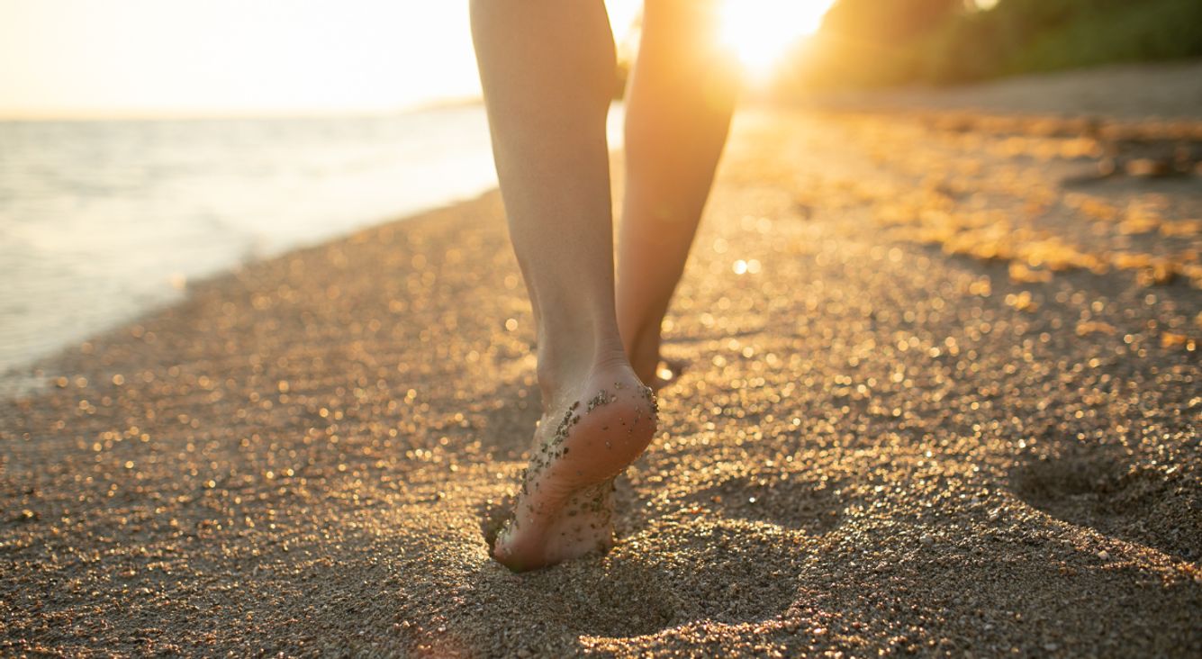 Person geht barfuß an Strand