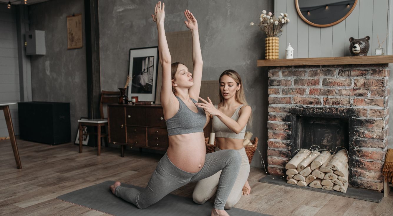 Schwangere Frau mit Trainerin beim Yoga