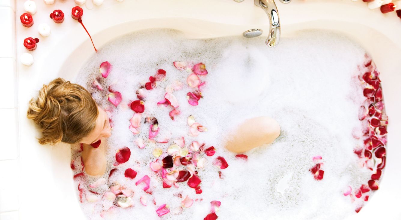 Person in Badewanne mit Rosenblättern