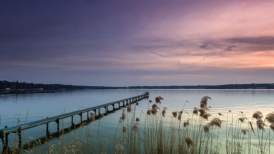 Steg über einem See bei Sonnenuntergang - Foto: Adobe Stock