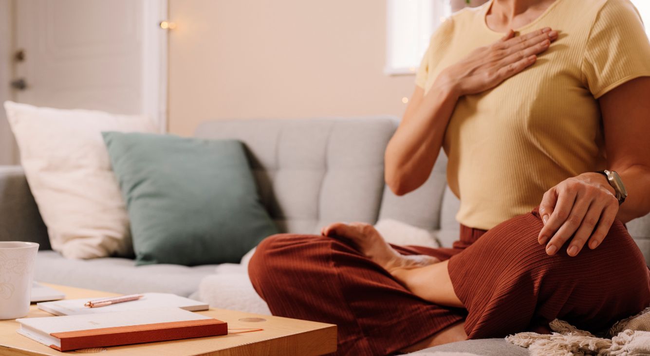 Person auf Couch mit Hand auf Brust