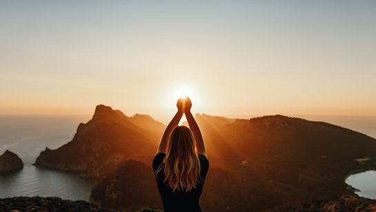 Frau steht auf einem Gipfel vor einem Sonnenaufgang - Foto: Canva / DianaHirsch