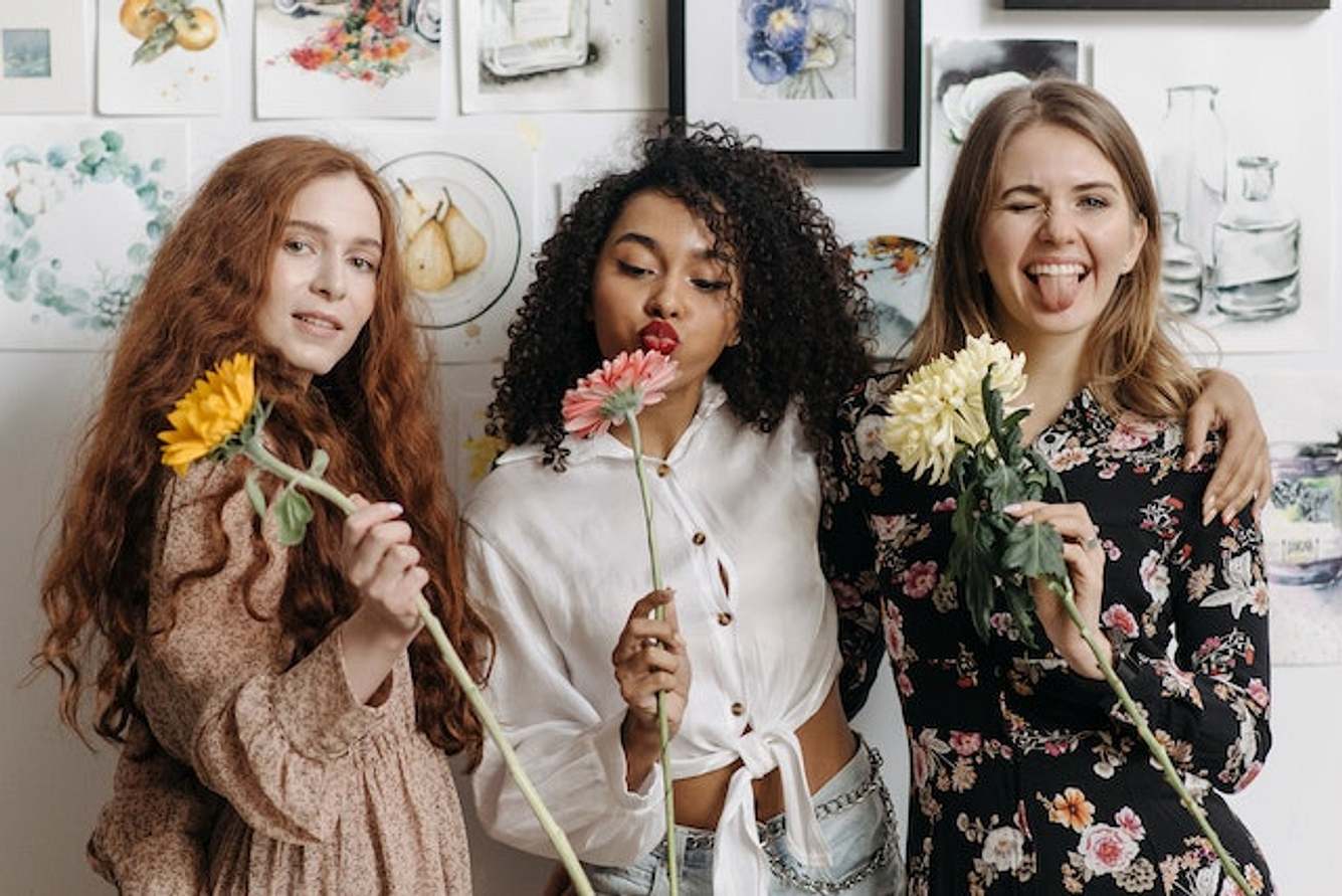 Drei Frauen vor Bilderwand mit Blumen