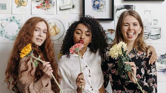 Drei Frauen vor Bilderwand mit Blumen - Foto: Pexels